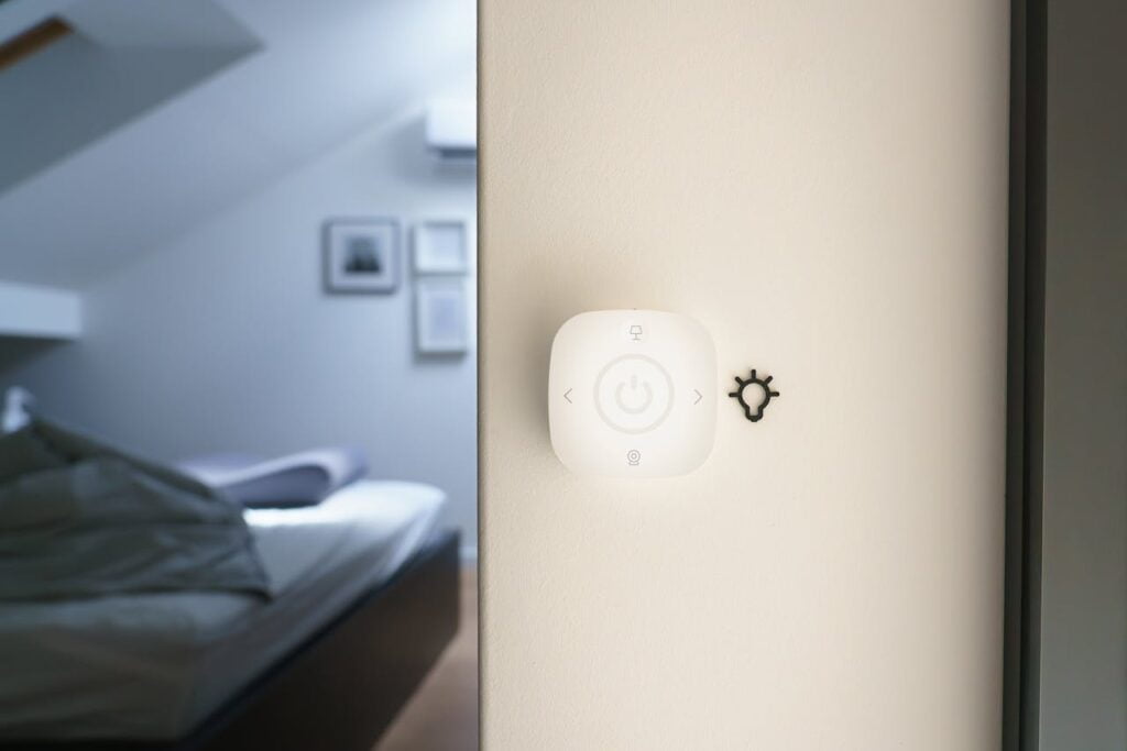 Vesta Smart Button a white square device with a light bulb on the wall